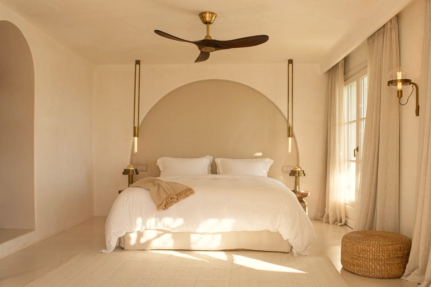 A bedroom at Viluz with an arched alcove headboard and morning light through linen curtains.