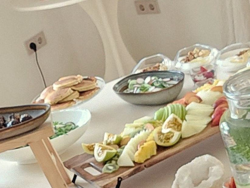 A long breakfast laid out at Viluz: bowls, boards, fruit and glasses on a white table.