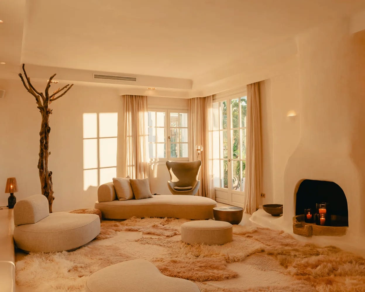 A limewashed sitting room at Viluz with floor cushions, sheepskins and a fire laid in the hearth.